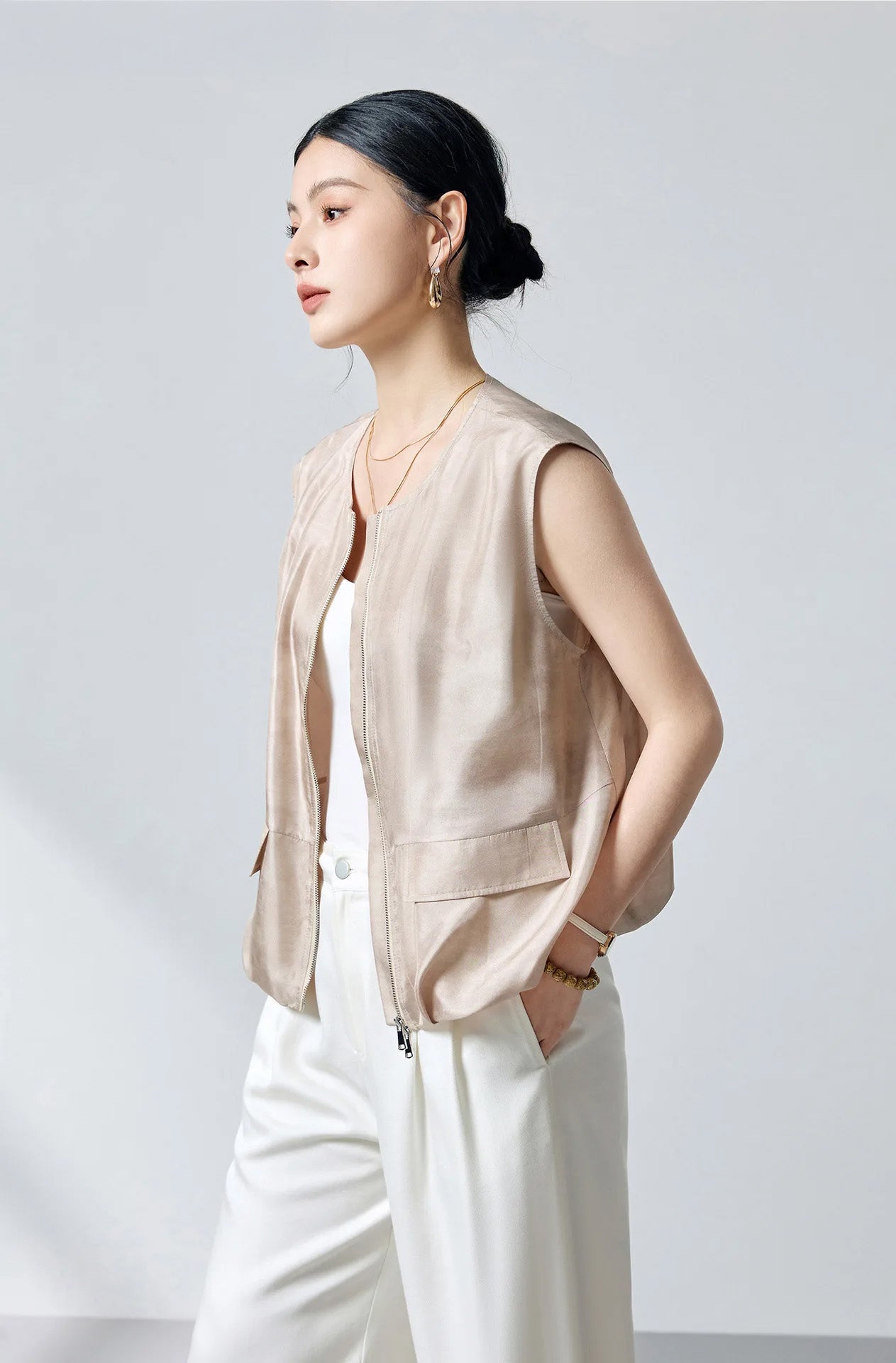 Three-quarter side view of the model showcasing the fluid silhouette of the sleeveless silk blouson jacket in Whispering Wind — From Borcelleclothes.