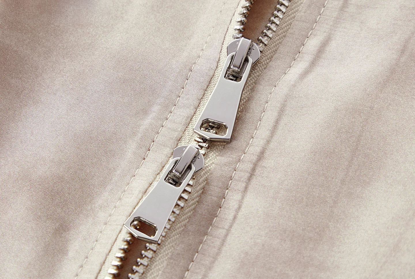 Close-up of the sleek two-way front zip pulls on the sleeveless Mulberry silk blouson jacket in Whispering Wind — From Borcelleclothes.