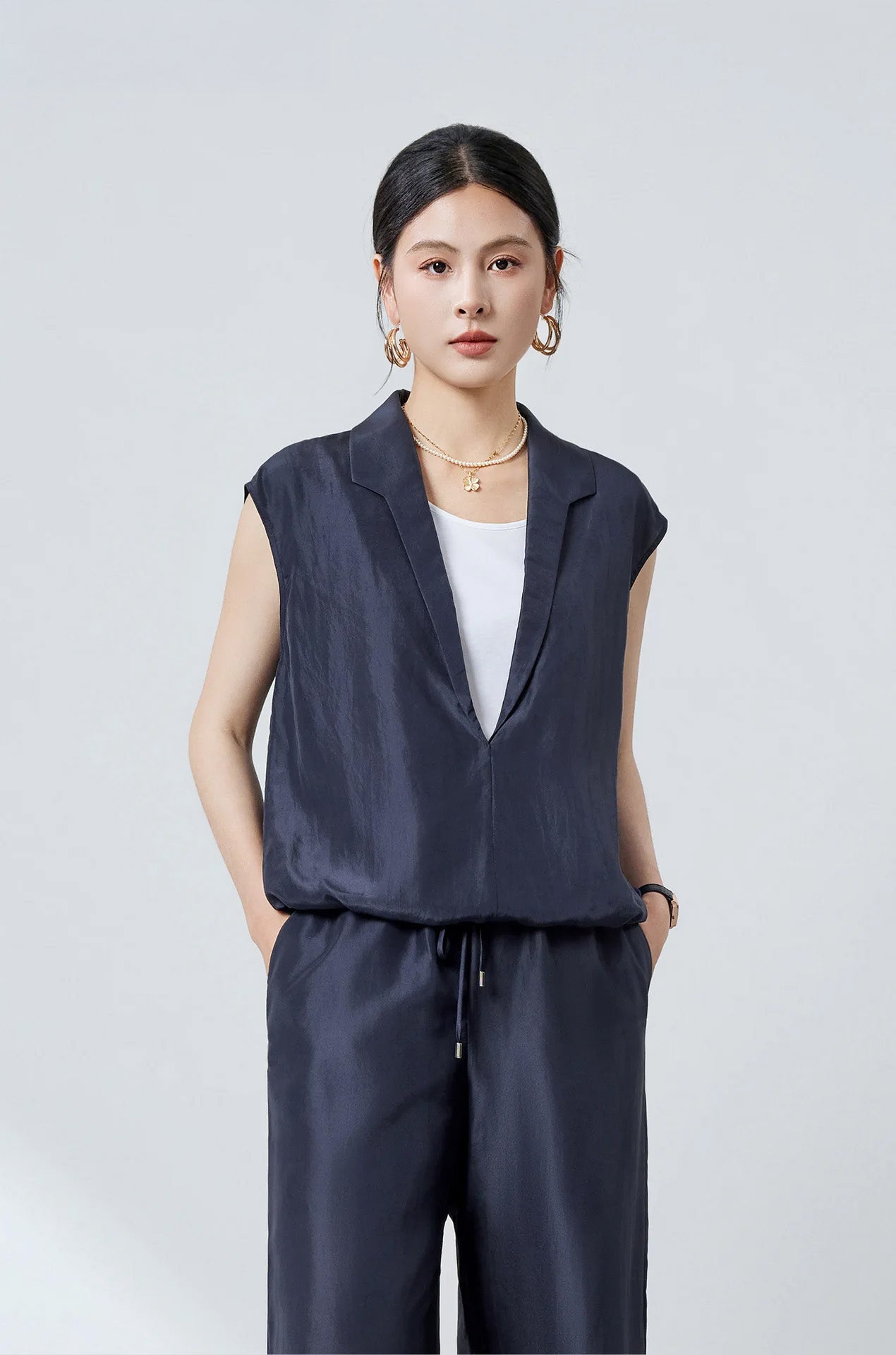 Front view of model wearing Blueprint layered silk blouse with hands in pockets of matching relaxed pants — From Borcelleclothes.