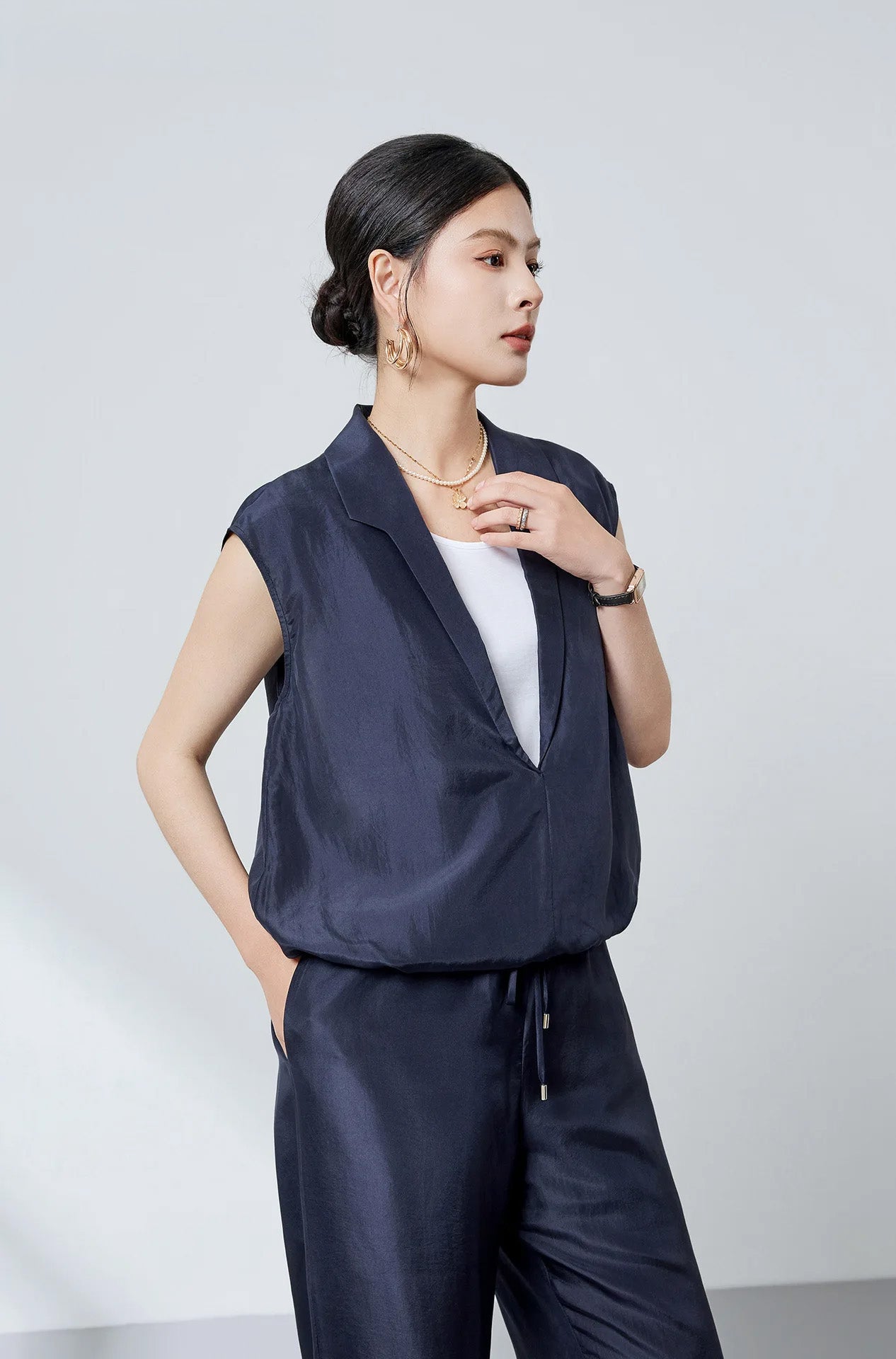Model wearing the Blueprint navy silk blouse with elongated stepped collar, hand resting near the neckline — From Borcelleclothes.