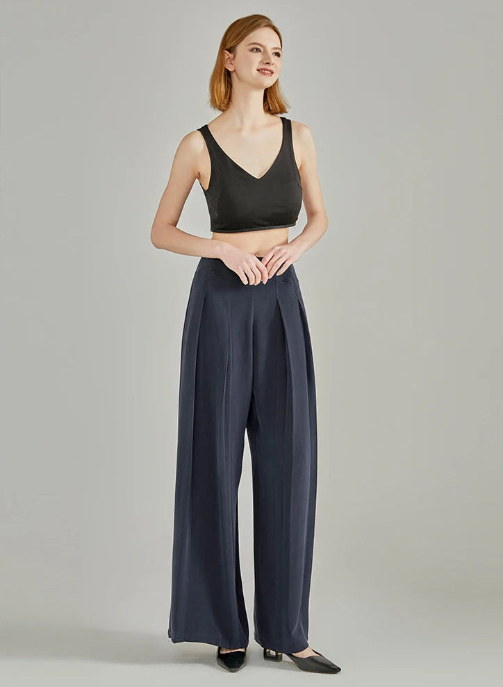 Full-length view of a model touching fingertips, wearing Dark Eyes Mulberry sandwashed silk crepe trousers — From Borcelleclothes.