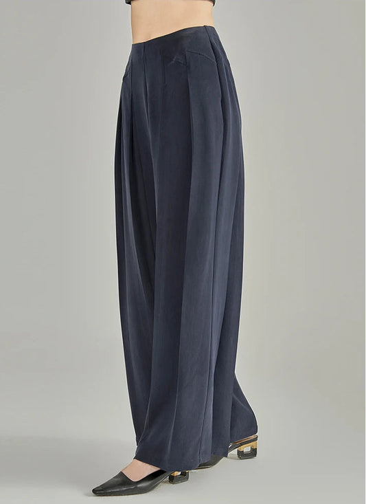 Side view of a model walking in wide-leg Dark Eyes sandwashed Mulberry silk trousers with stepped yokes — From Borcelleclothes.