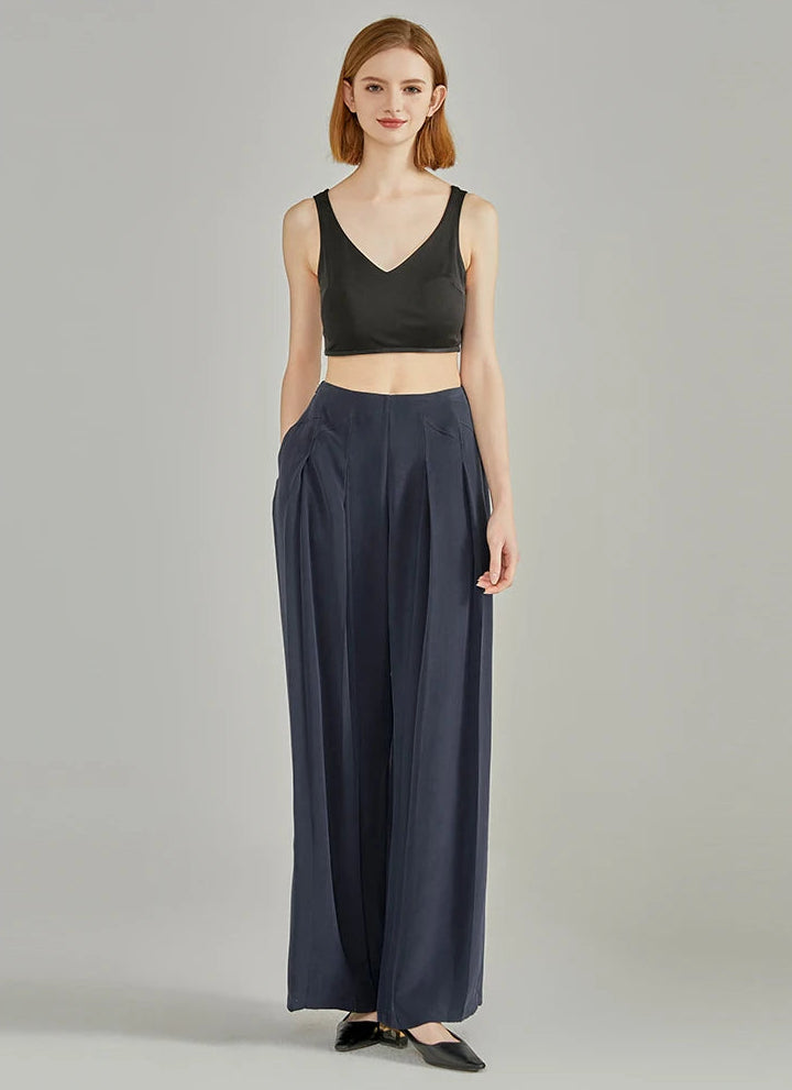 Full-height standing pose of a model with hands behind back in floor-length Dark Eyes silk trousers — From Borcelleclothes.