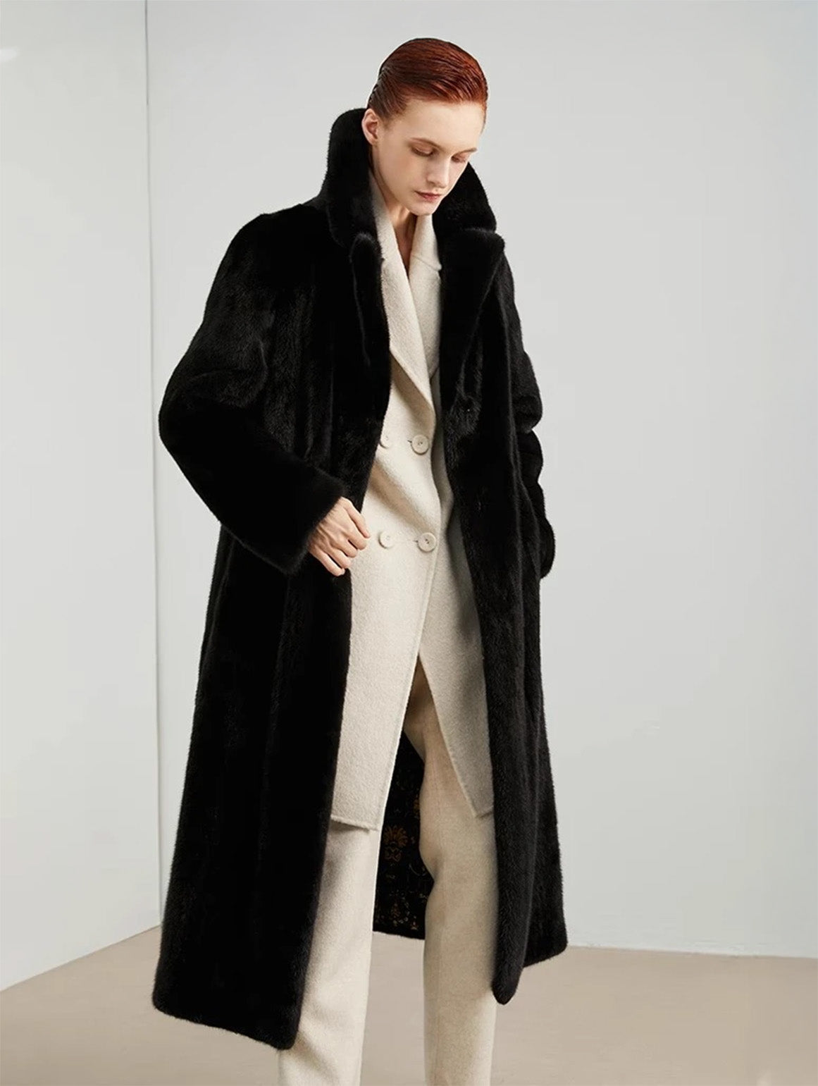 Model wearing straight mink coat in rich black, one hand in pocket, looking down — From Borcelleclothes.