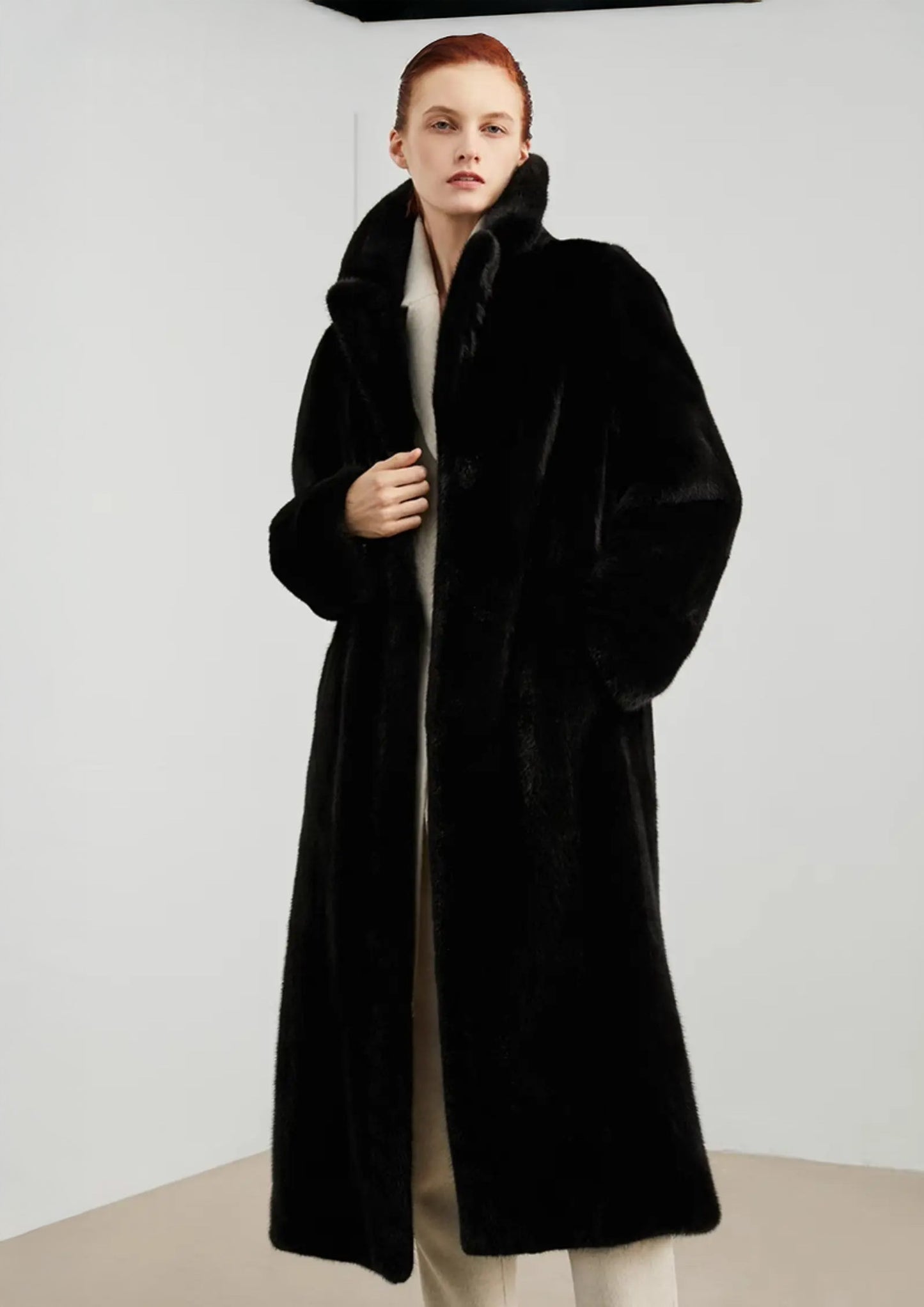 Model with one hand resting in the side pocket of a straight mink coat in rich black — From Borcelleclothes.