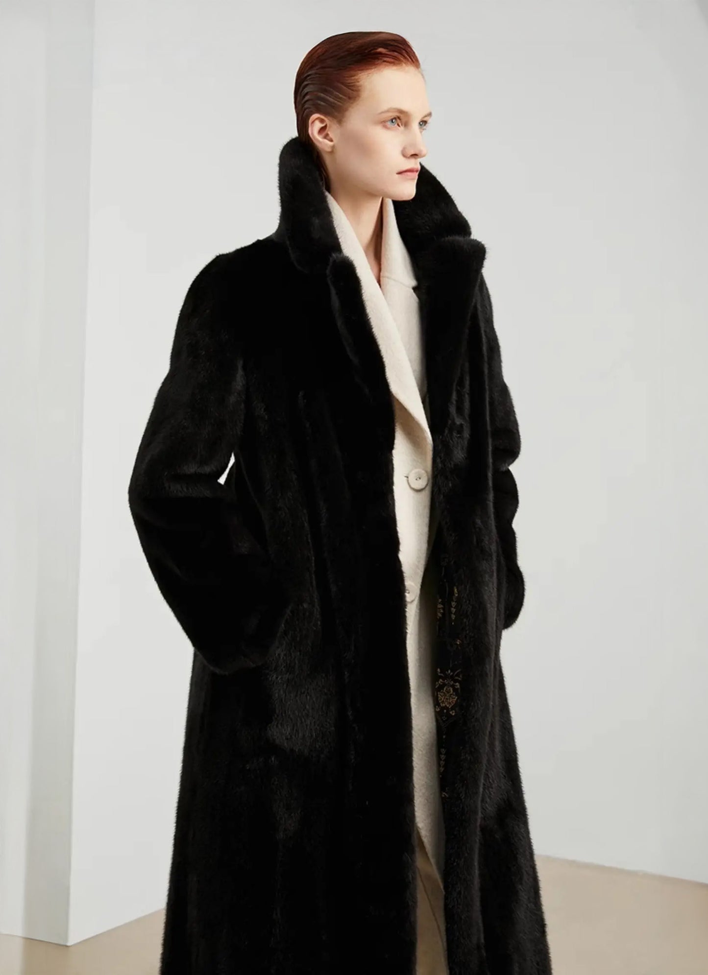 Model standing with both hands in the pockets of a straight mink coat in rich black — From Borcelleclothes.