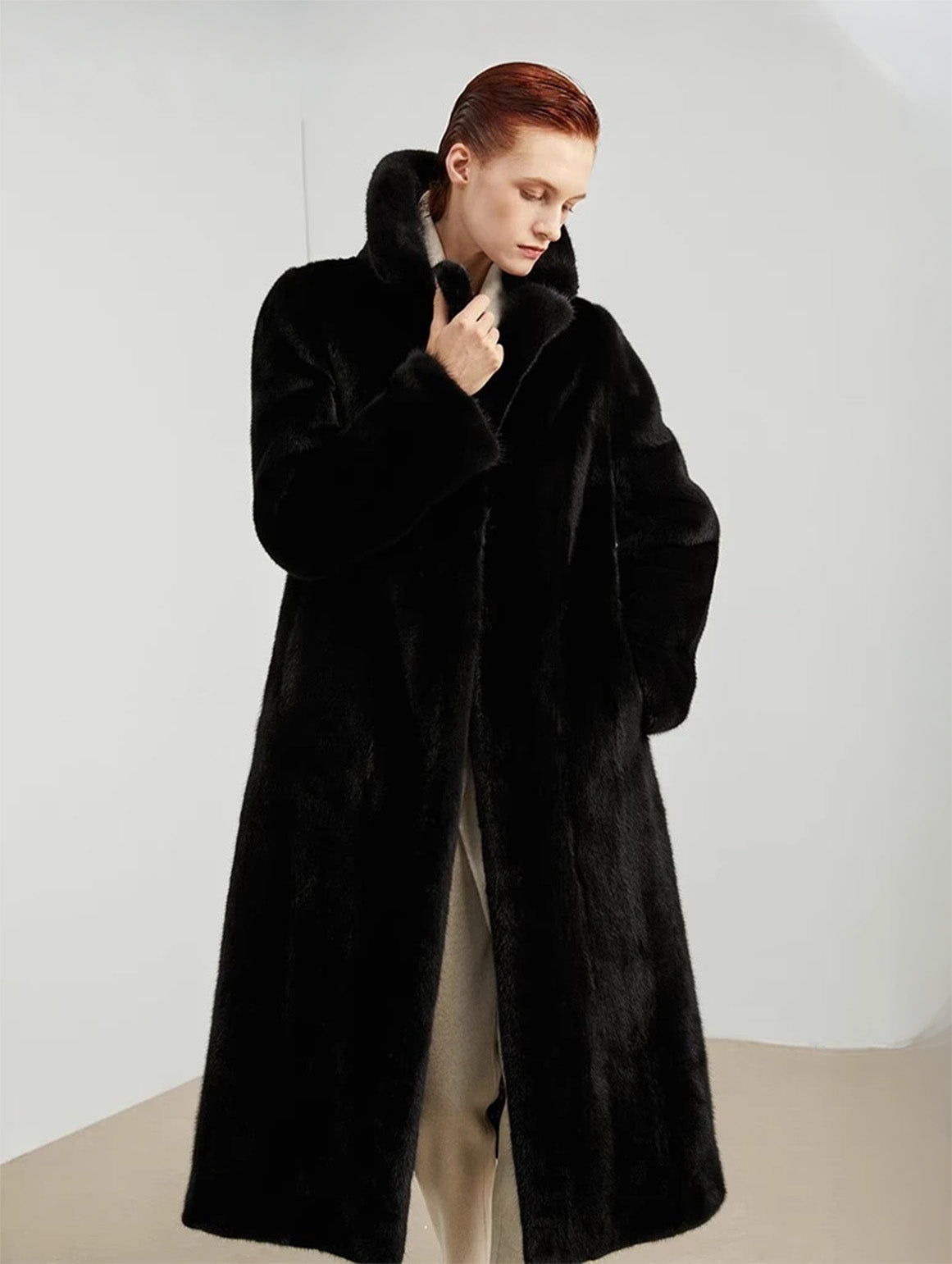 Model in straight mink coat in rich black, holding one lapel and looking downward — From Borcelleclothes.