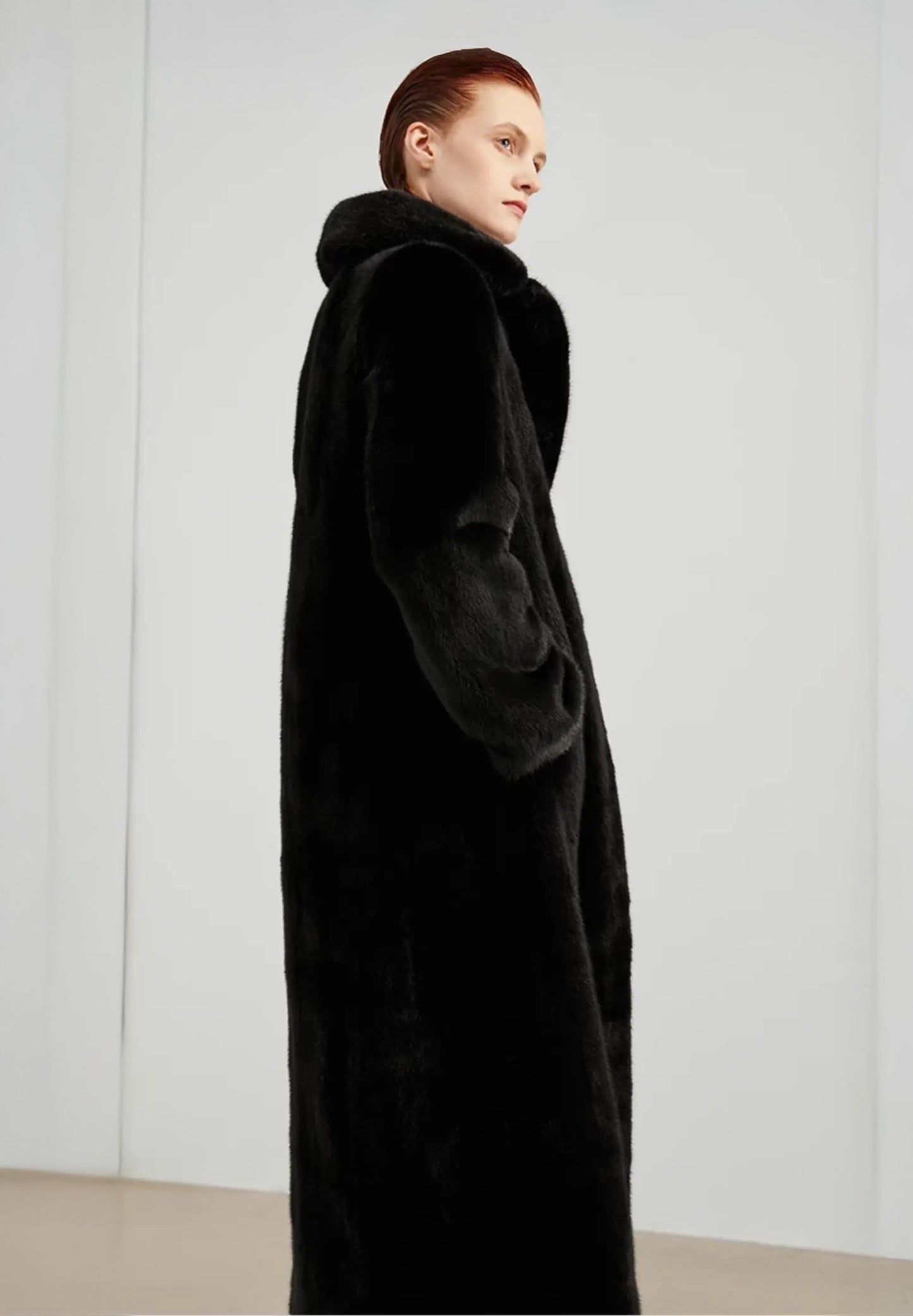 Side profile of model wearing a straight mink coat in rich black — From Borcelleclothes.