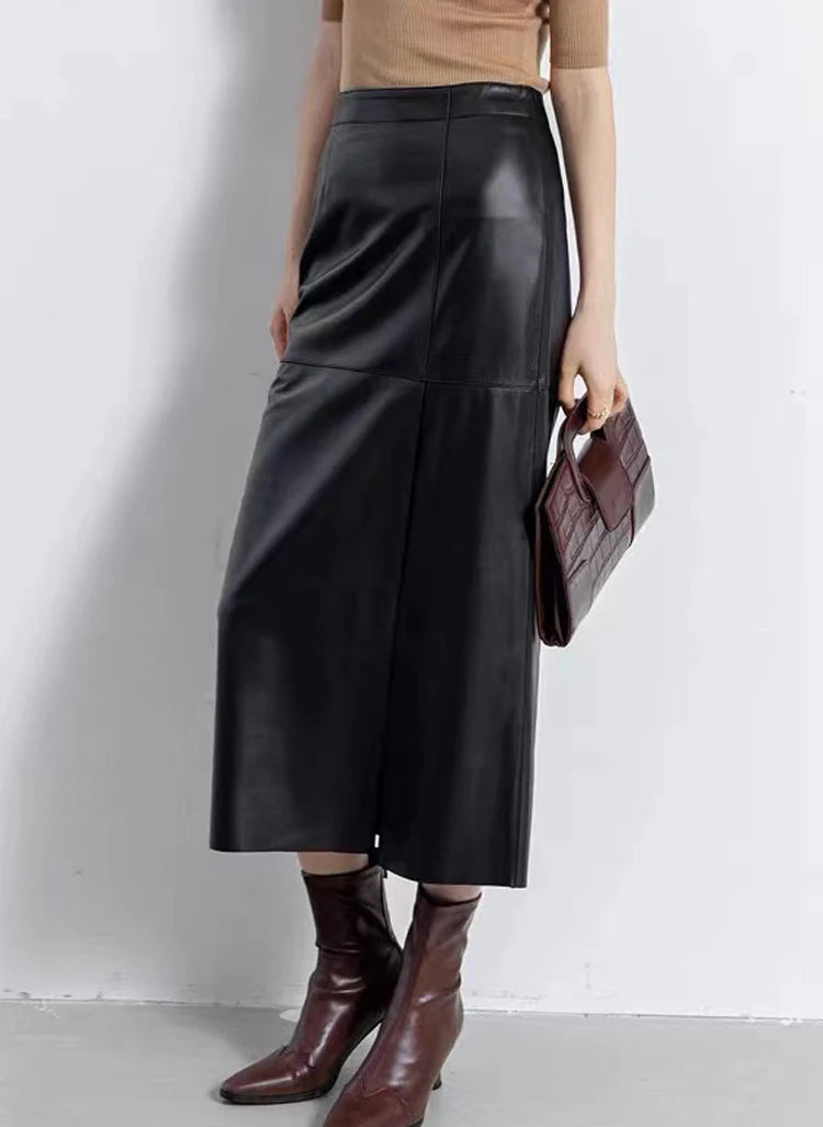Model leaning against a wall wearing a straight sheepskin midi skirt with an asymmetric slit in Dark Horse — From Borcelleclothes.
