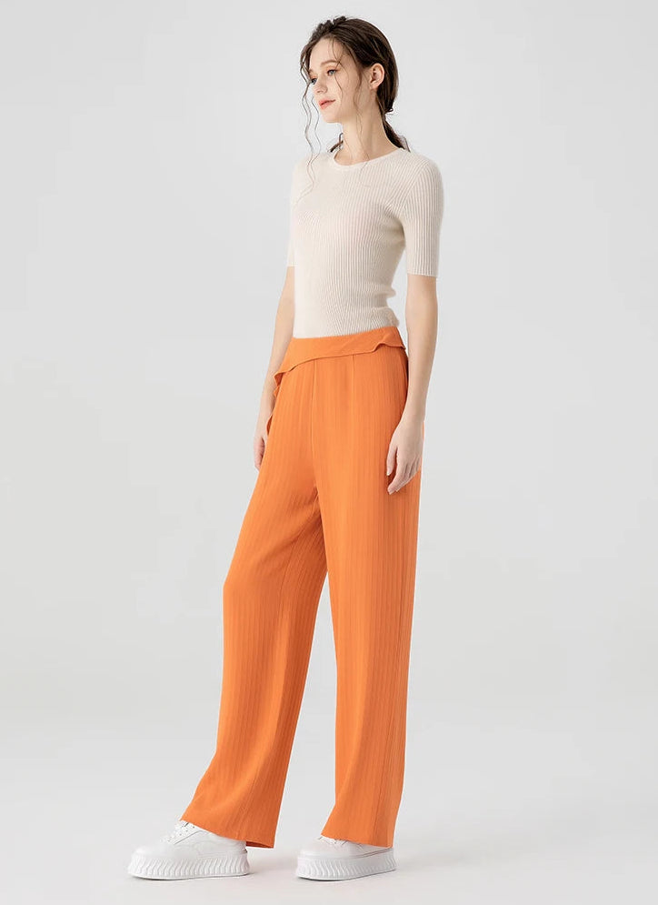 Full-height right side view of a woman wearing Fragrant Cloud silk trousers, featuring an asymmetrical waist overlay extending down the thigh — From Borcelleclothes.