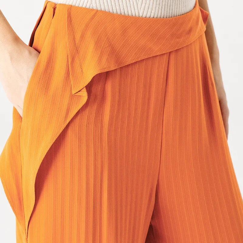 Detail shot of a woman's hand in the discreet side seam pocket of orange silk jacquard trousers with a hidden right-side zipper — From Borcelleclothes.