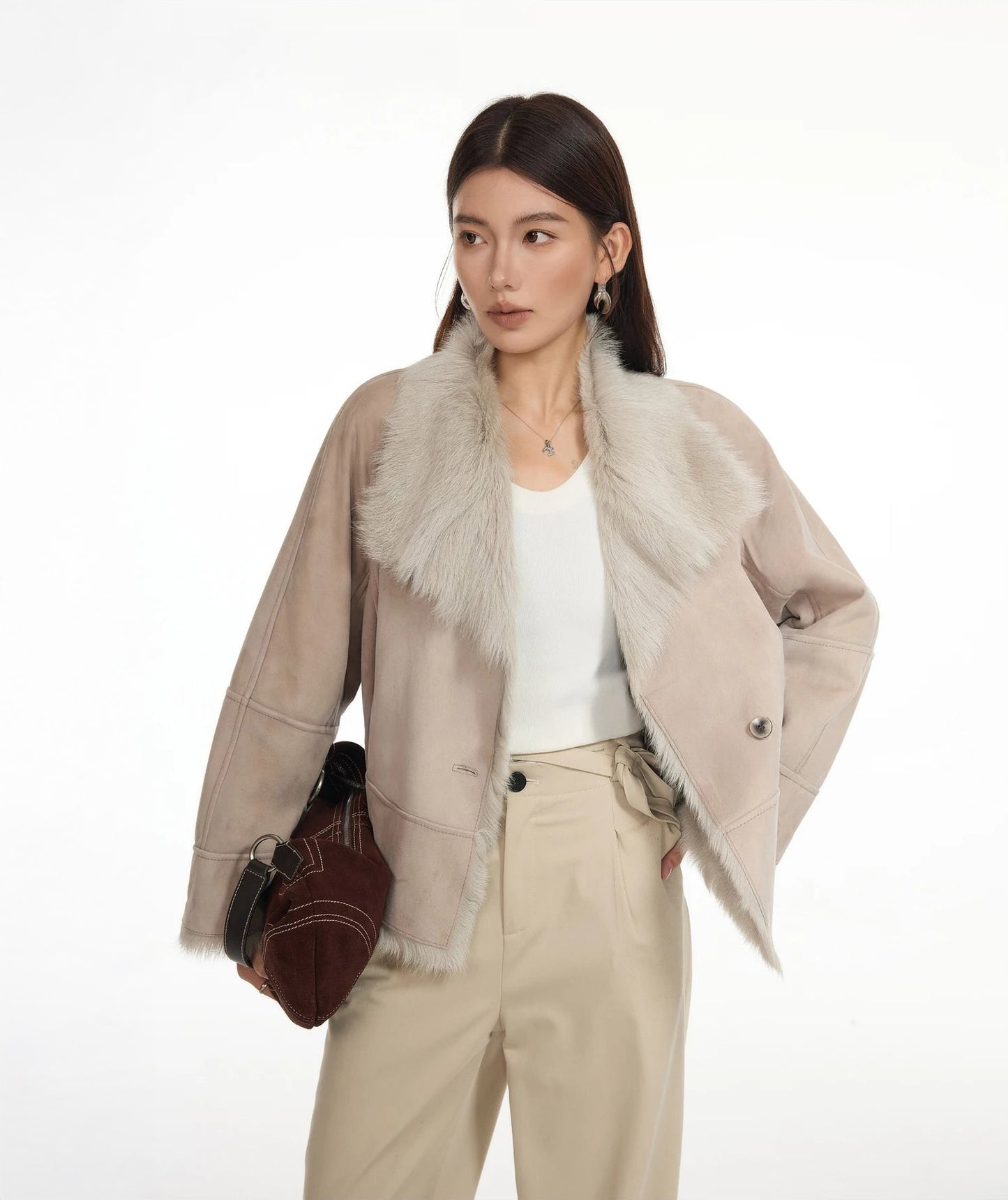 Model looking to the side while holding a bag, wearing suede-faced goatskin jacket in Fond Memory — From Borcelleclothes.