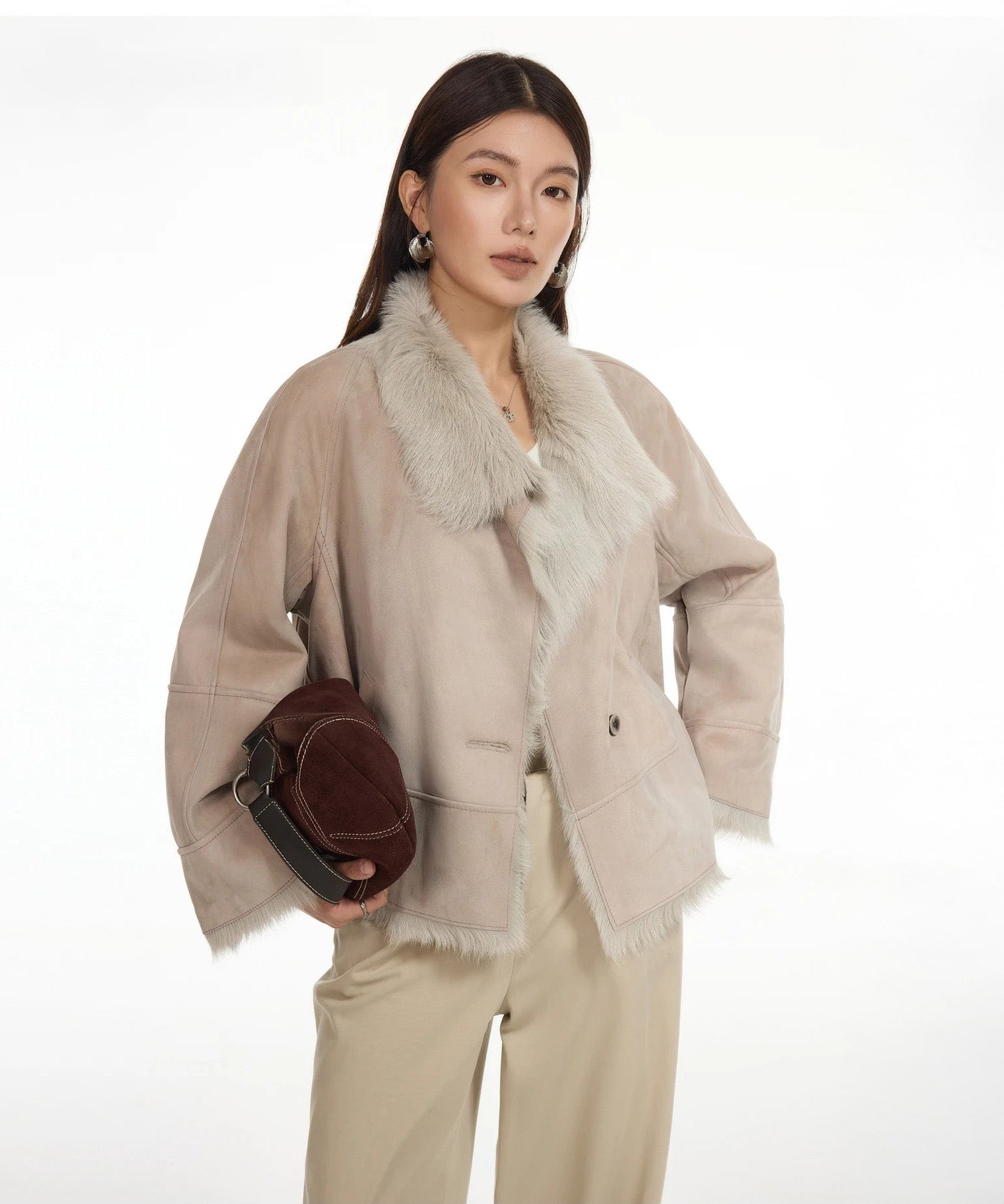 Model holding a bag while wearing suede-faced goatskin jacket in Fond Memory — From Borcelleclothes.