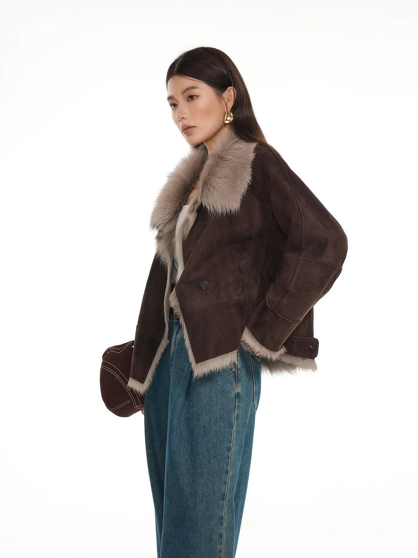 Model holding bag, suede-faced goatskin jacket in Toorak, other hand at hip — From Borcelleclothes.