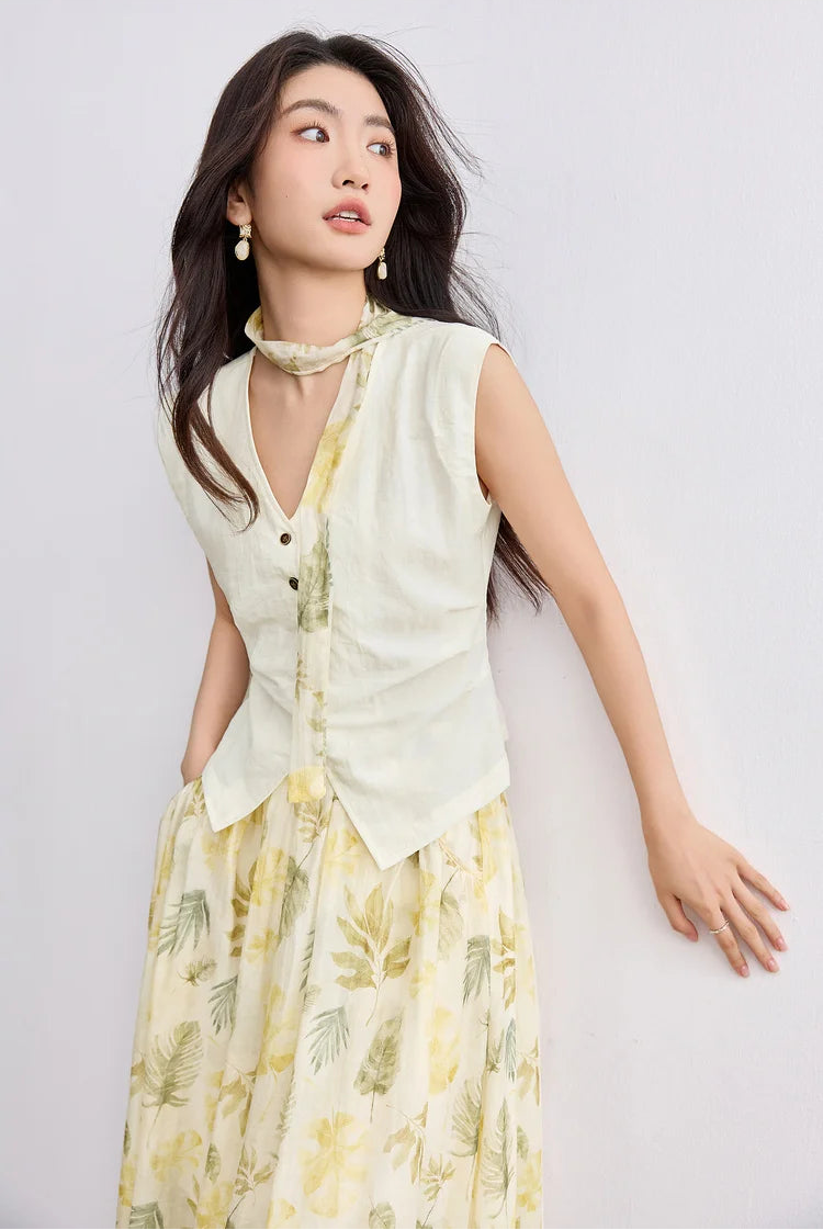 A woman leaning against a wall and looking aside, wearing the architectural Sydney Breeze vest and skirt — From Borcelleclothes.