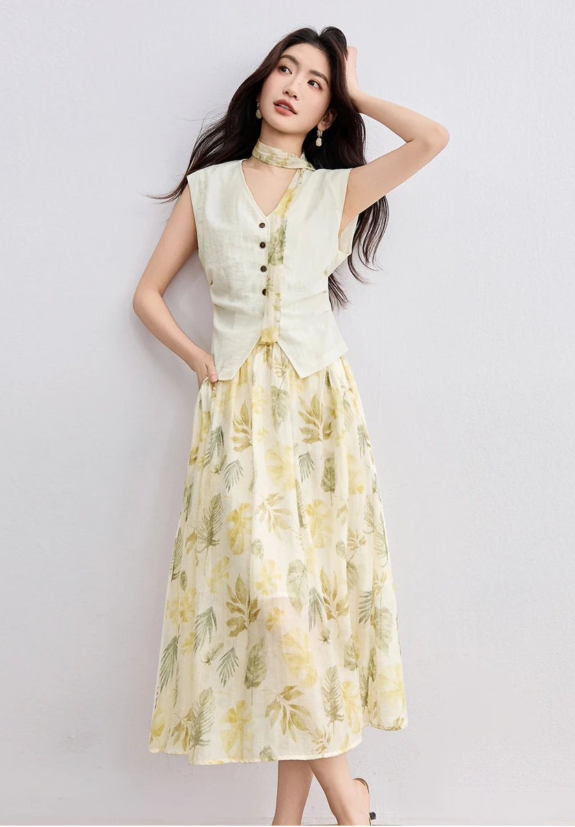A woman in a soft yellow Sydney Breeze set, touching her hair with crossed legs, showcasing the fluid drape of the chiffon skirt — From Borcelleclothes.