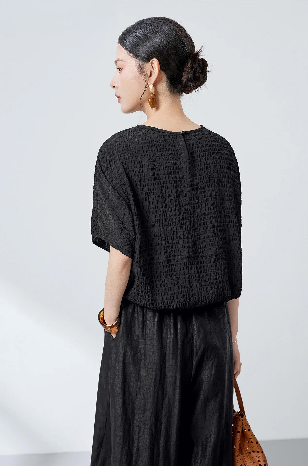 Back view of a woman wearing a black Mulberry silk blouse with a slit neckline — From Borcelleclothes.