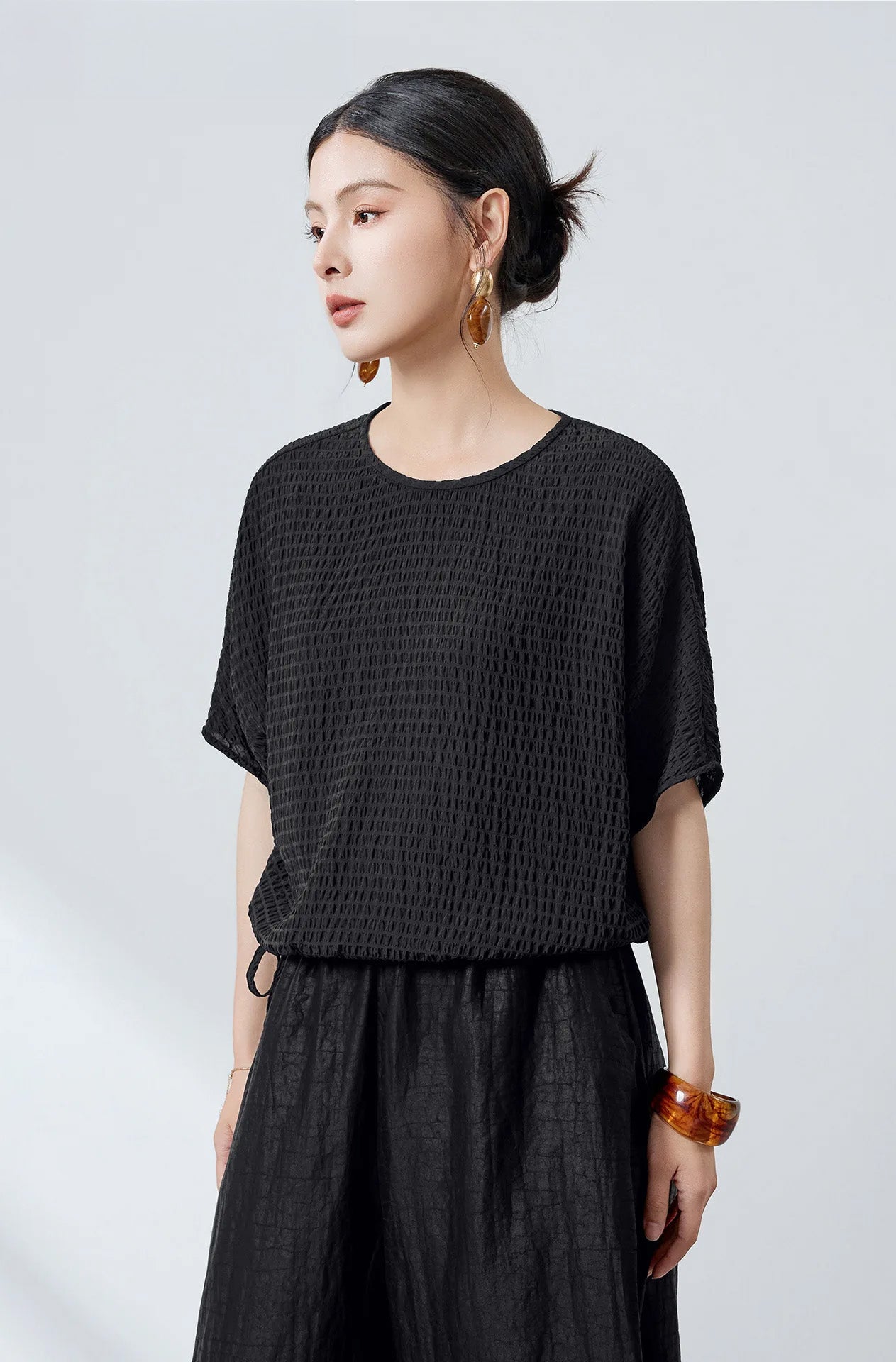 A woman looking to the side in a black textured stripe Mulberry silk batwing blouse — From Borcelleclothes.