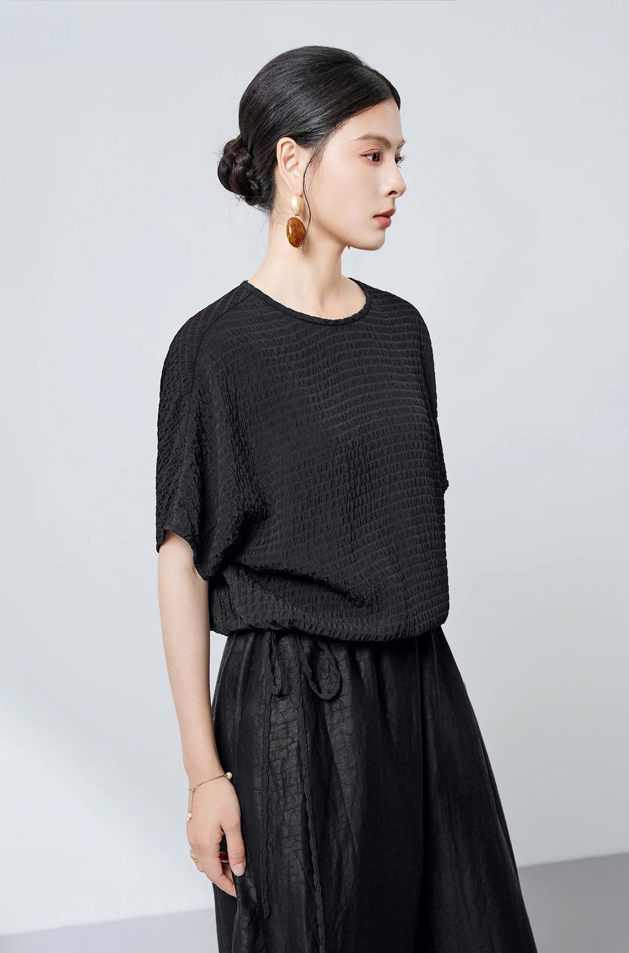 A woman turned slightly to the side wearing a black textured stripe Mulberry silk blouse — From Borcelleclothes.