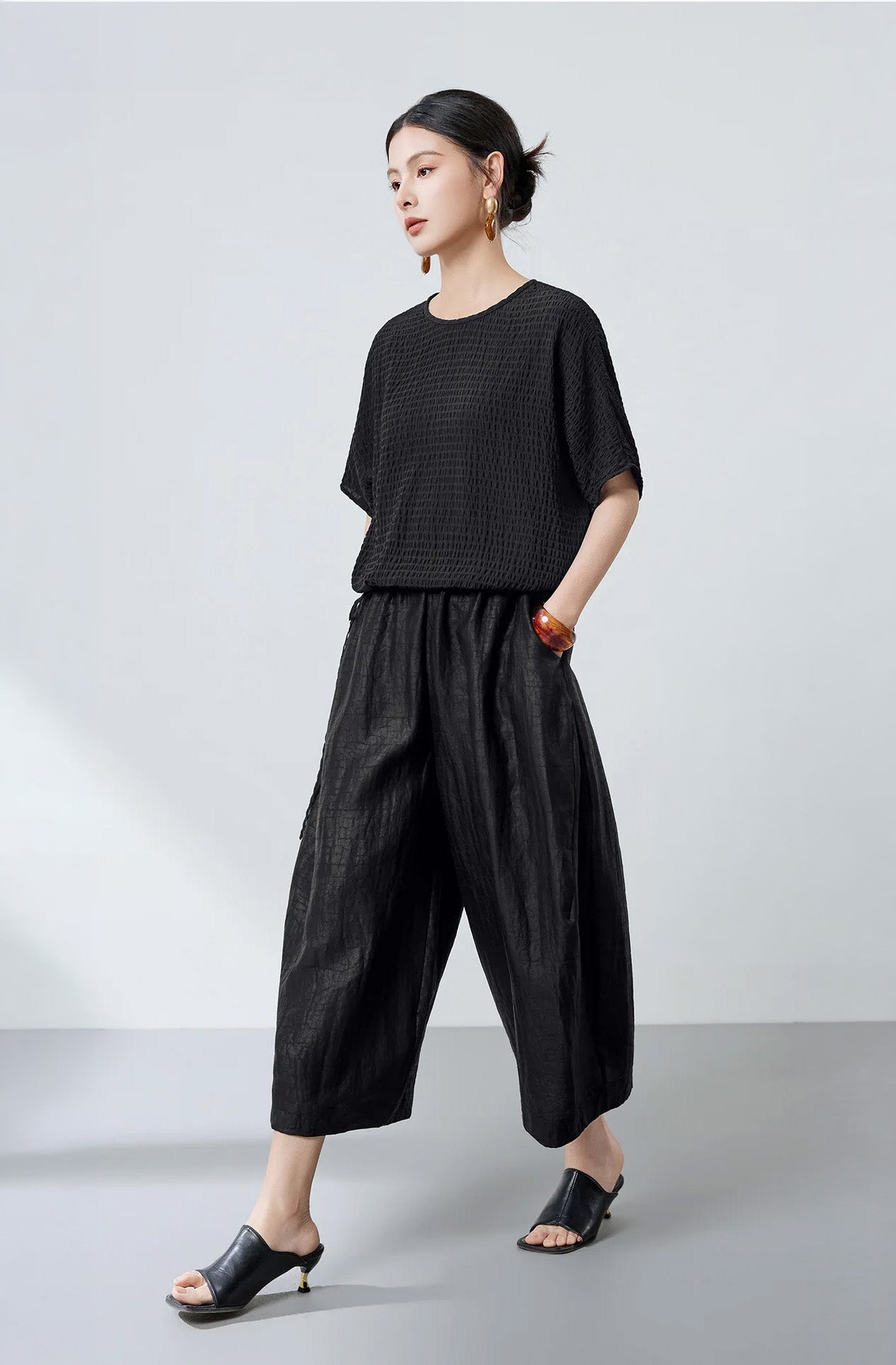 Side view of a woman walking in a black textured stripe Mulberry silk blouse — From Borcelleclothes.