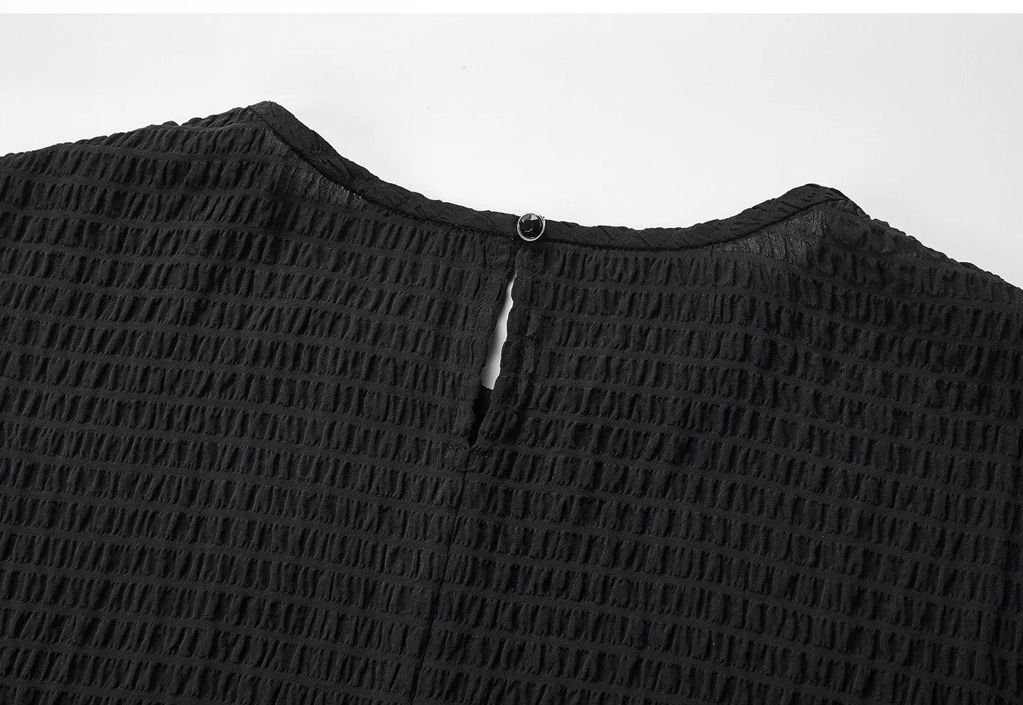Detail of the back neckline slit with a decorative button on a black silk blouse — From Borcelleclothes.