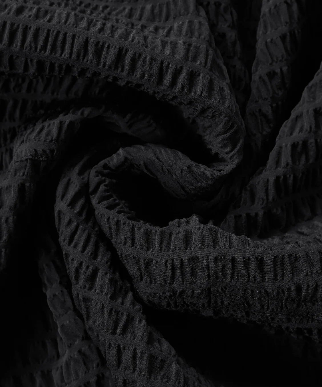 Close-up of the 3D spiral-folded textured Mulberry silk fabric on a black blouse — From Borcelleclothes.