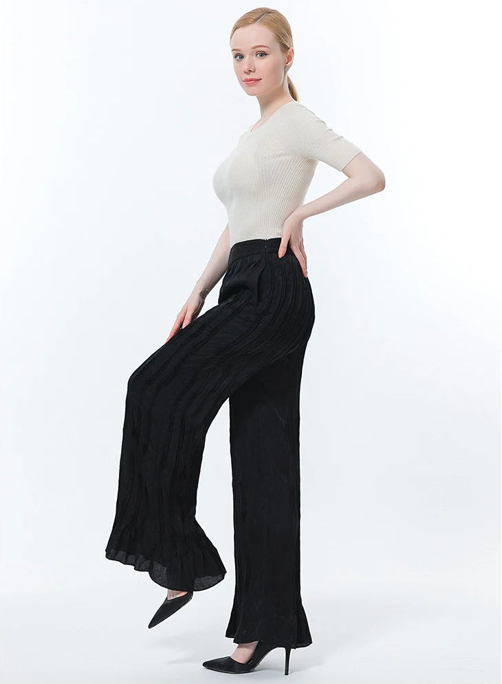 Full-length side view of silk tucked trousers in Hide-and-Seek on model posing with a raised bent leg — From Borcelleclothes.