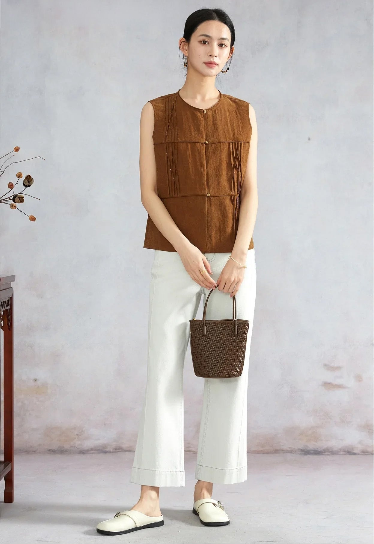 Model holding a woven bag with both hands wearing Tucked Xiangyunsha Silk Blouse in Cinnamon Amulet — From Borcelleclothes.