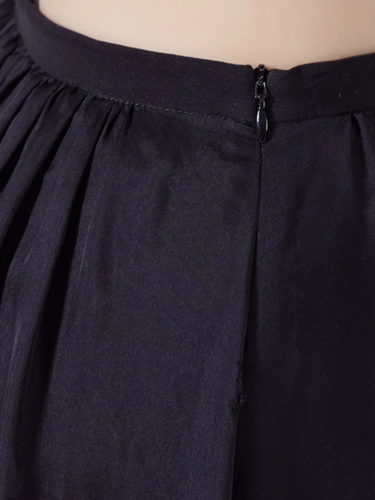 Detailed view of the integrated invisible side zipper on the waistband of pleated silk skirt — From Borcelleclothes.