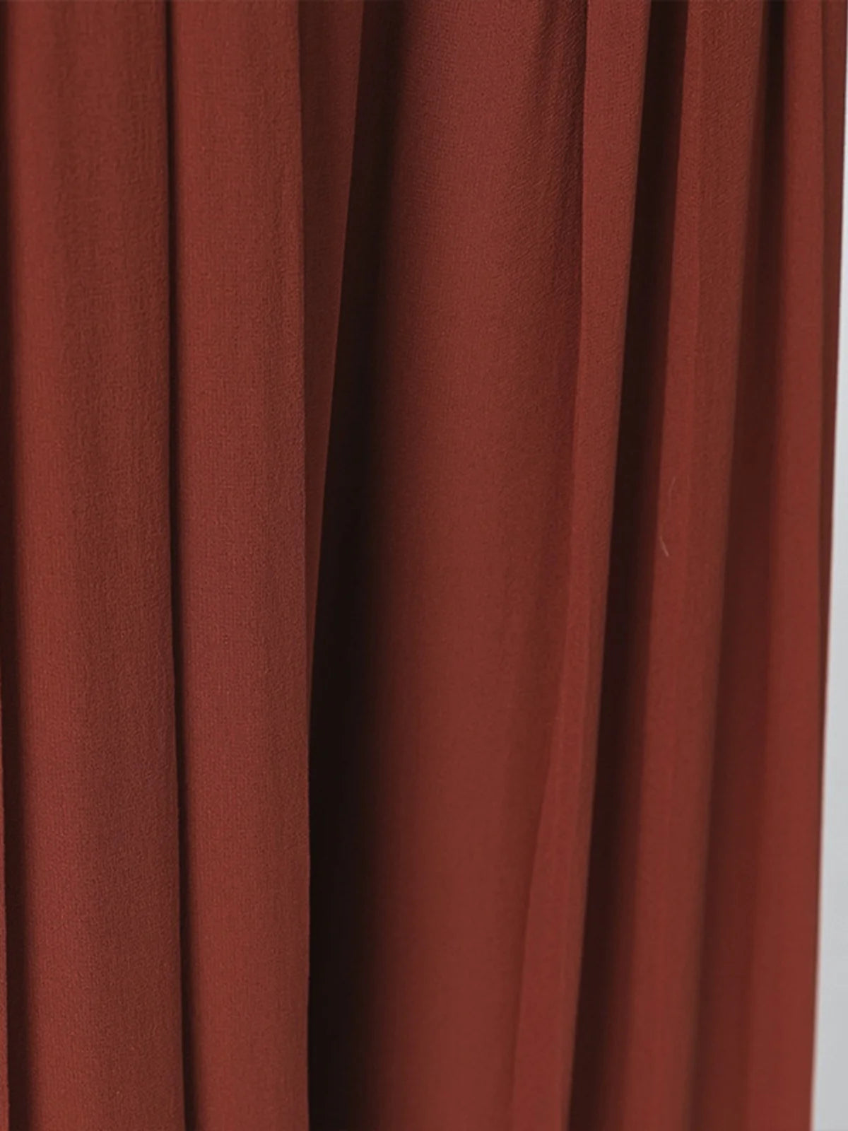 Close-up of the fluid drape on two-layer pleated Mulberry silk georgette trousers in Contradictory Terracotta — From Borcelleclothes.