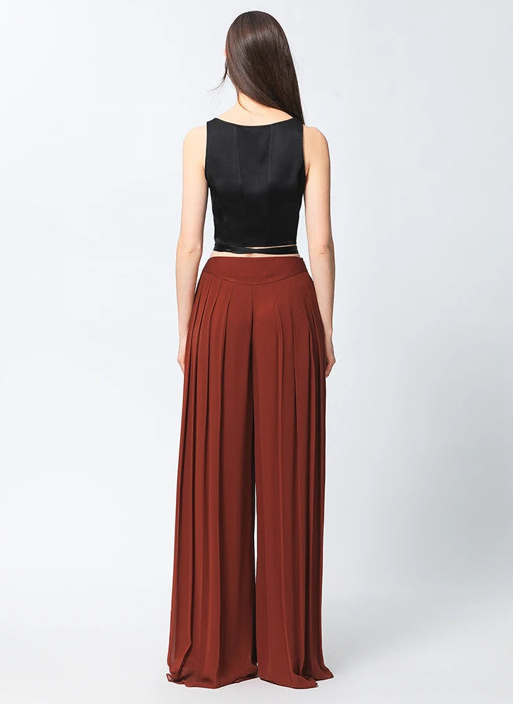 Full-length back view of two-layer pleated Mulberry silk georgette trousers in Contradictory Terracotta — From Borcelleclothes.