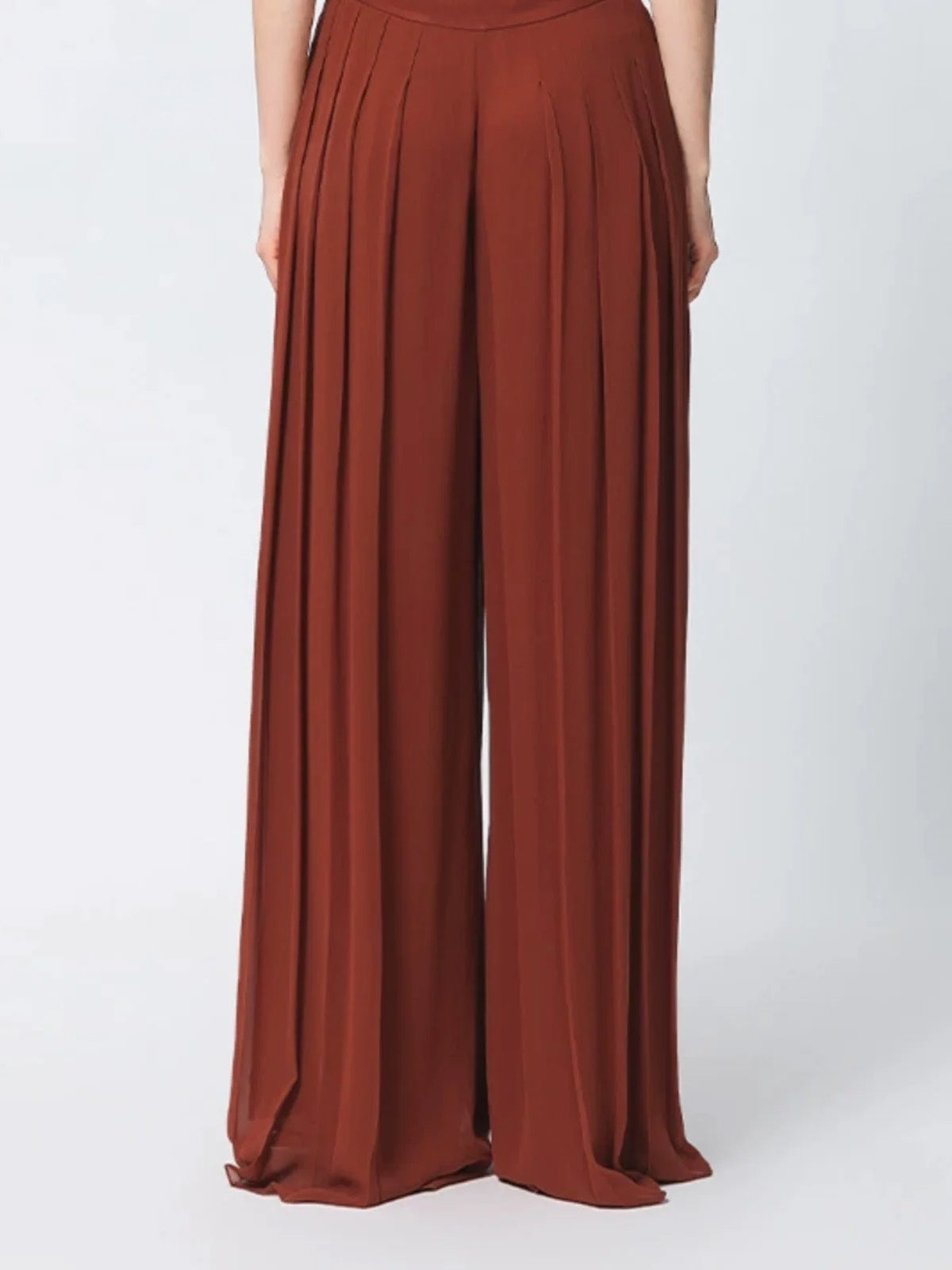 Back view of model wearing two-layer pleated Mulberry silk georgette trousers in Contradictory Terracotta — From Borcelleclothes.