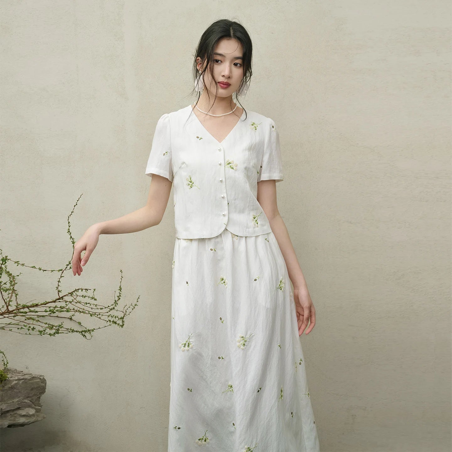A woman with a gently raised arm in the Utsugi Blossom set, revealing the slightly gathered sleeve heads and the fluidity of the Bride’s Silence white viscose — From Borcelleclothes.
