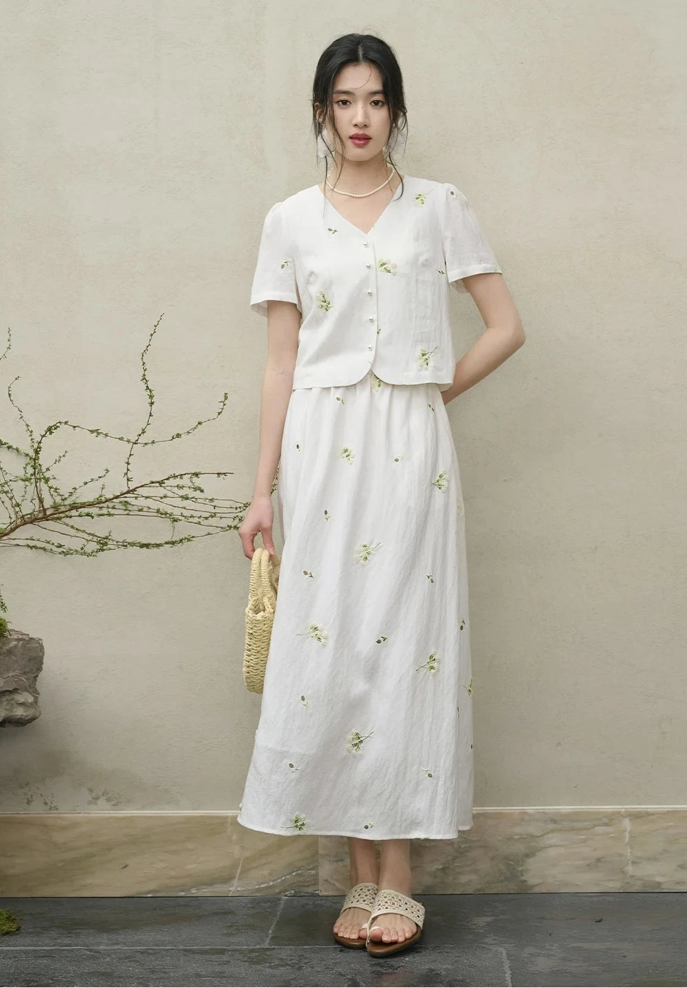 A woman standing gracefully in the Utsugi Blossom set, one hand resting behind her back, highlighting the clean silhouette and Bride’s Silence white tone — From Borcelleclothes.
