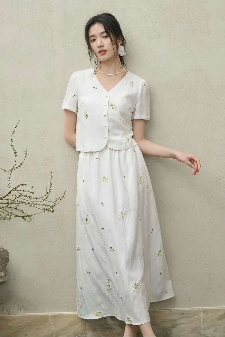 A woman leaning softly against a wall in the Utsugi Blossom viscose set, creating a relaxed yet sophisticated image in Bride’s Silence white — From Borcelleclothes.