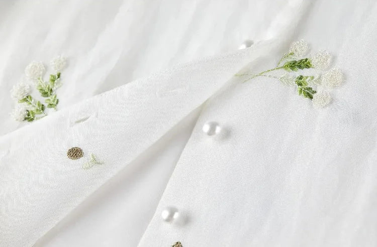 A detailed view of the Utsugi Blossom top with unbuttoned pearl buttons, showcasing the artisanal finish of the Bride’s Silence white set — From Borcelleclothes.