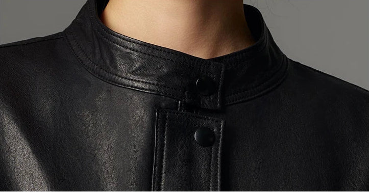 Close-up detail of the neat band collar fastening with a single snap on the vegetable-tanned sheepskin neckline — From Borcelleclothes.