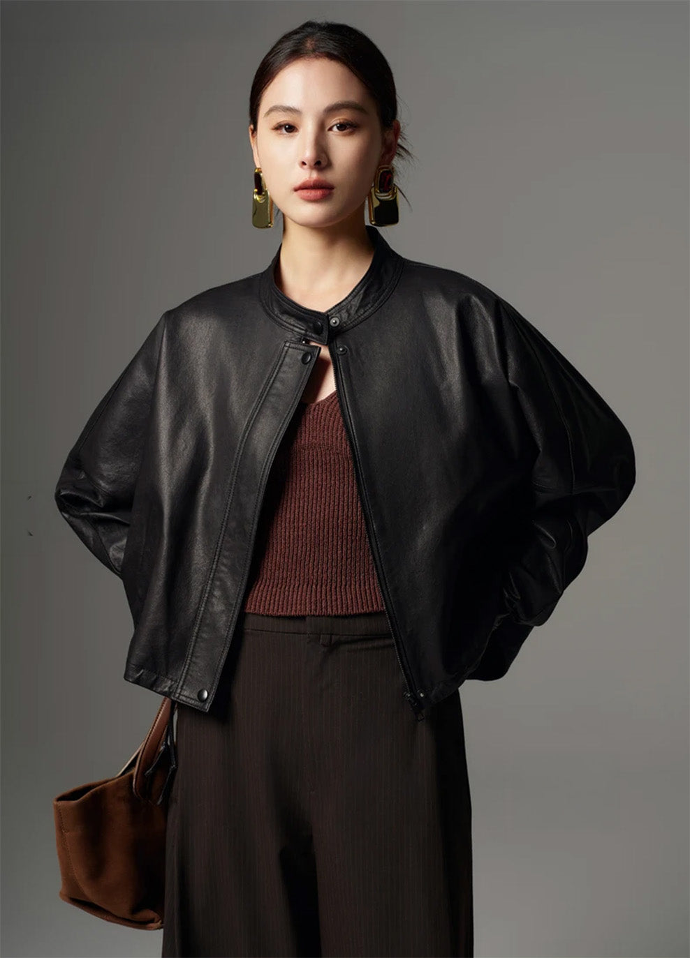 Model posing with hands behind her back, displaying the clean front placket and band collar of the jacket — From Borcelleclothes.
