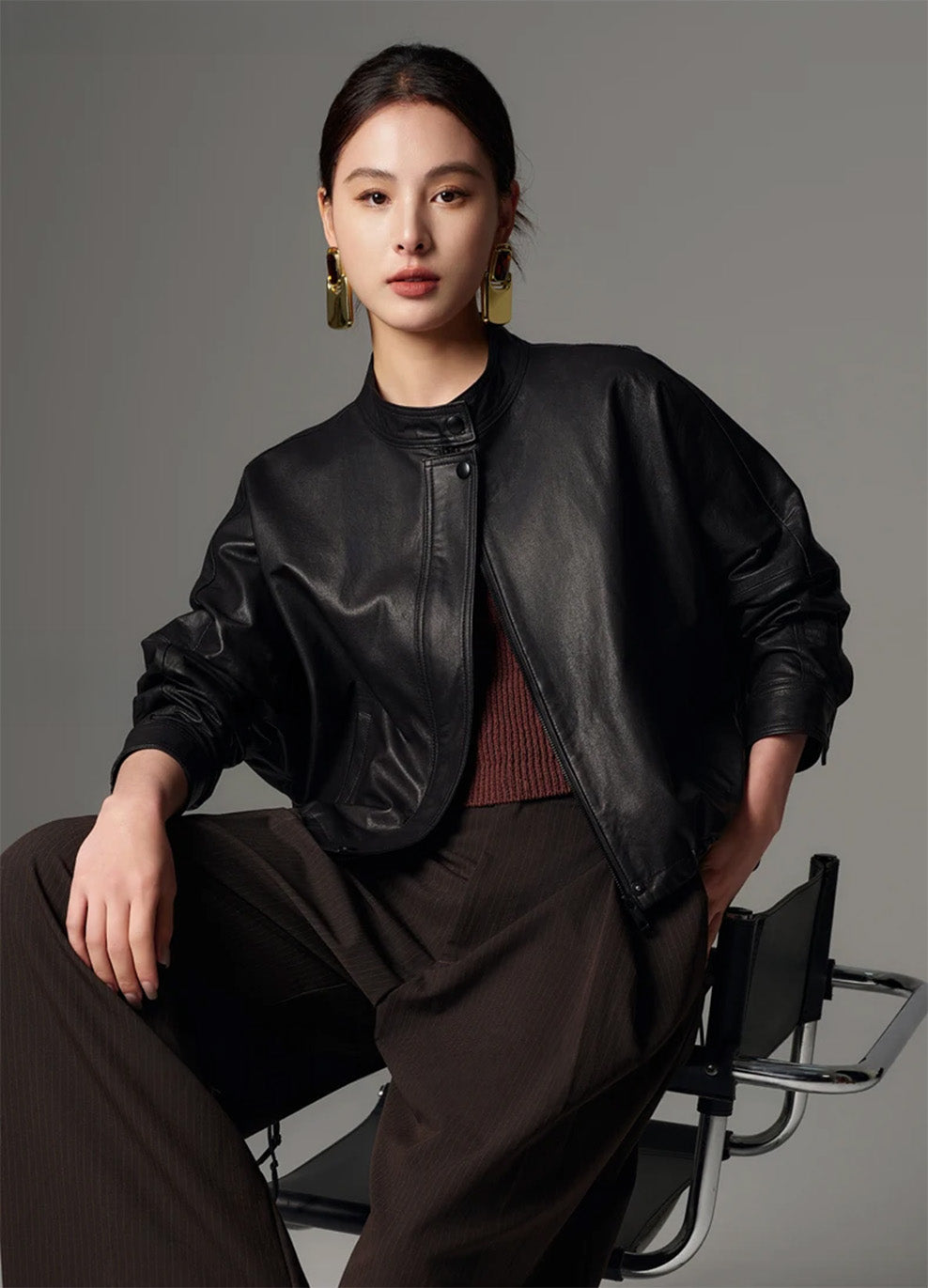 Model sitting on a chair wearing the black vegetable-tanned sheepskin cropped jacket with draped kimono sleeves — From Borcelleclothes.