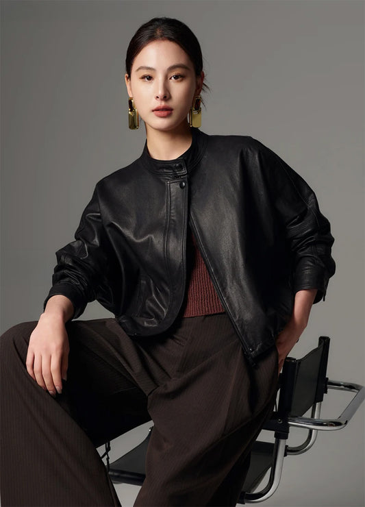 Model sitting on a chair wearing the black vegetable-tanned sheepskin cropped jacket with draped kimono sleeves — From Borcelleclothes.