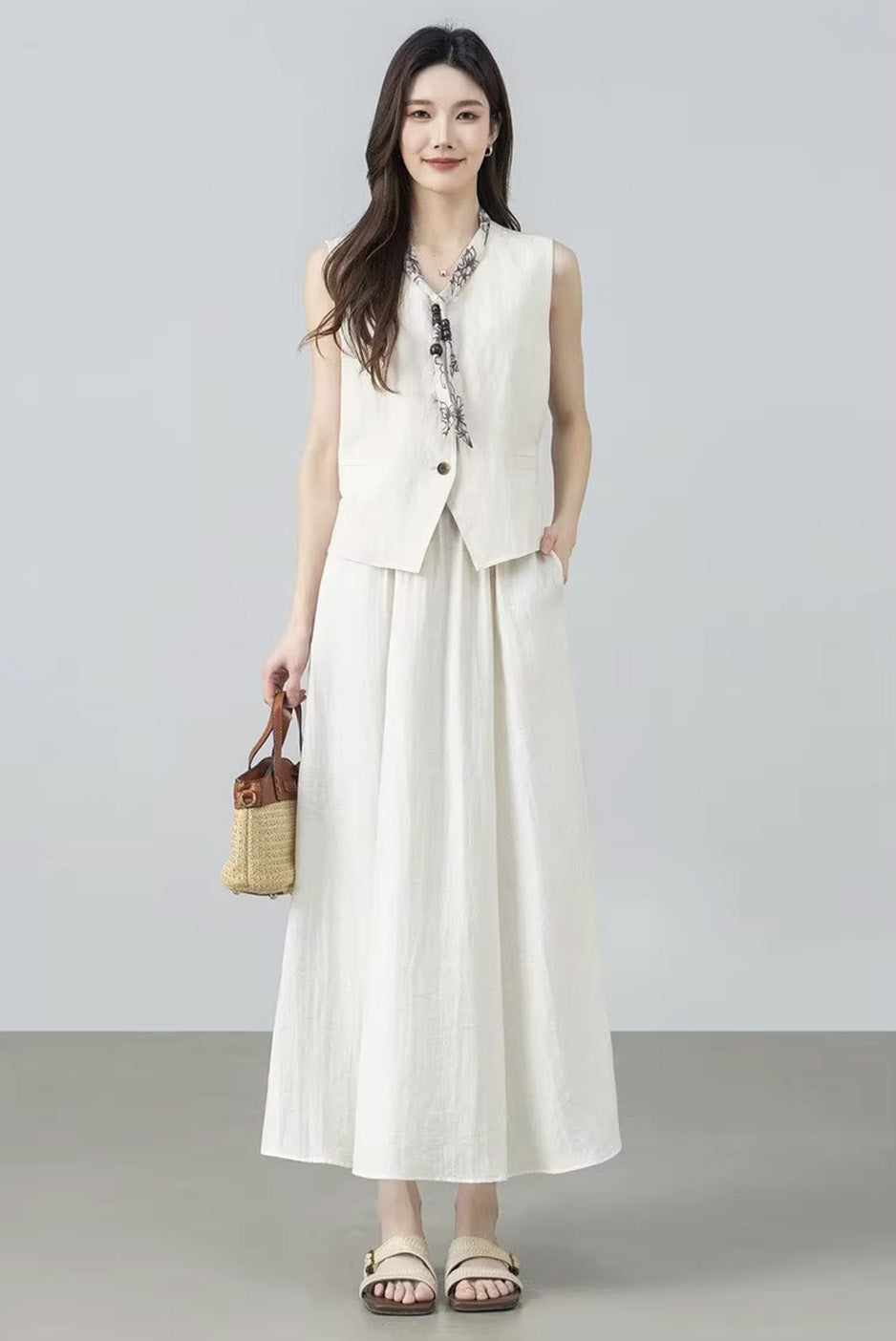 Model holding a bag with one hand in her pocket, wearing the white viscose blend gathered midi skirt in Azir Fog — From Borcelleclothes.
