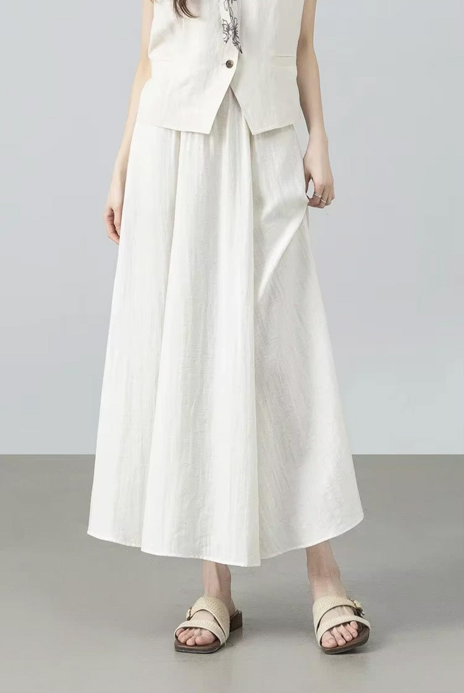 Model touching the delicate crinkled texture of the women's viscose-linen blend gathered skirt in Azir Fog — From Borcelleclothes.