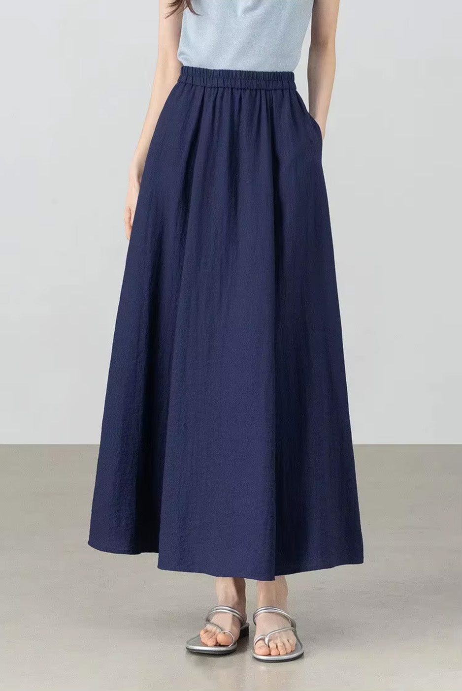 Model with her hand in the side seam pocket of the navy blue gathered midi skirt in Shurima Oasis — From Borcelleclothes.