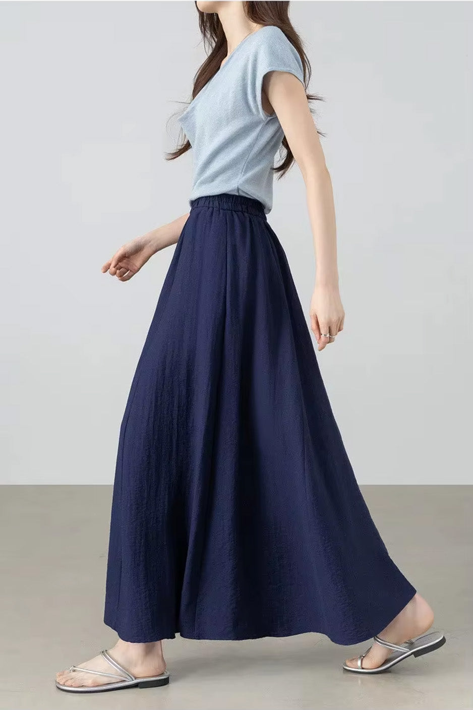 Elegant side view of a model walking in the flared viscose-linen blend gathered skirt in Shurima Oasis — From Borcelleclothes.
