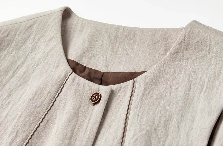Detail of the deep round neckline and the wave-stitch embroidery on the truffle-colored vest — From Borcelleclothes.