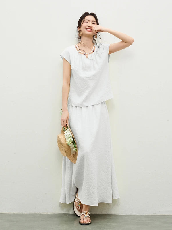 A woman wearing the "Beaded Spell" set in pure white, touching her lips, showcasing the delicate beaded detail — From Borcelleclothes.