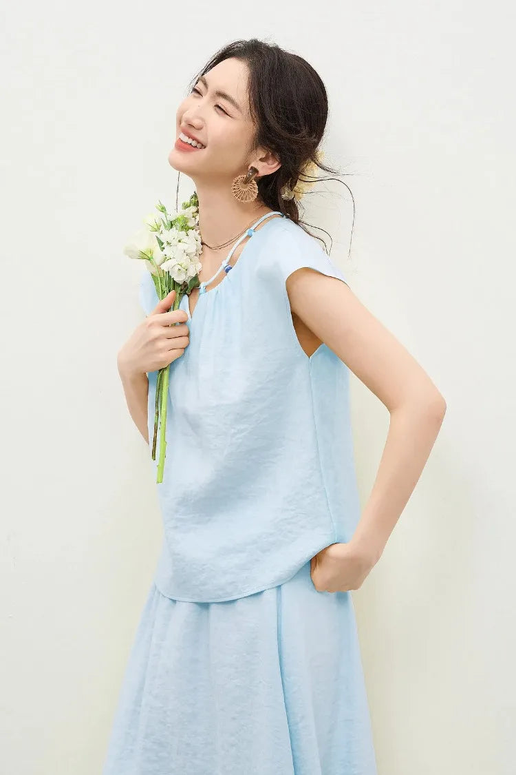 A woman wearing the sky blue viscose set holding a bouquet of flowers, reflecting a poetic and natural aesthetic — From Borcelleclothes.
