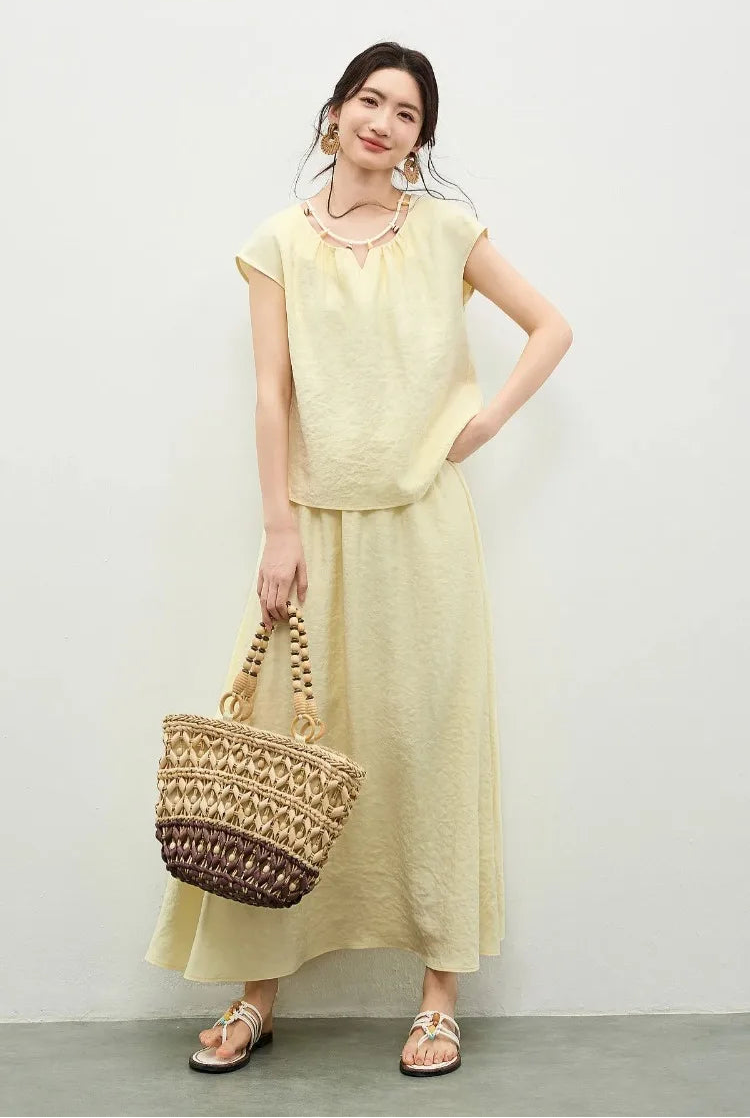 A woman in a sunny yellow viscose set holding a woven bag, showcasing a relaxed yet sophisticated summer look — From Borcelleclothes.