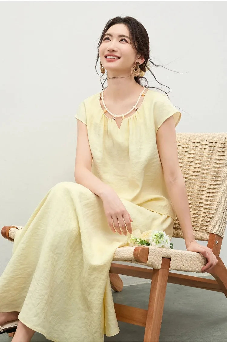 A woman wearing the yellow viscose set, sitting on a bench and looking up, embodying a moment of serene contemplation — From Borcelleclothes.