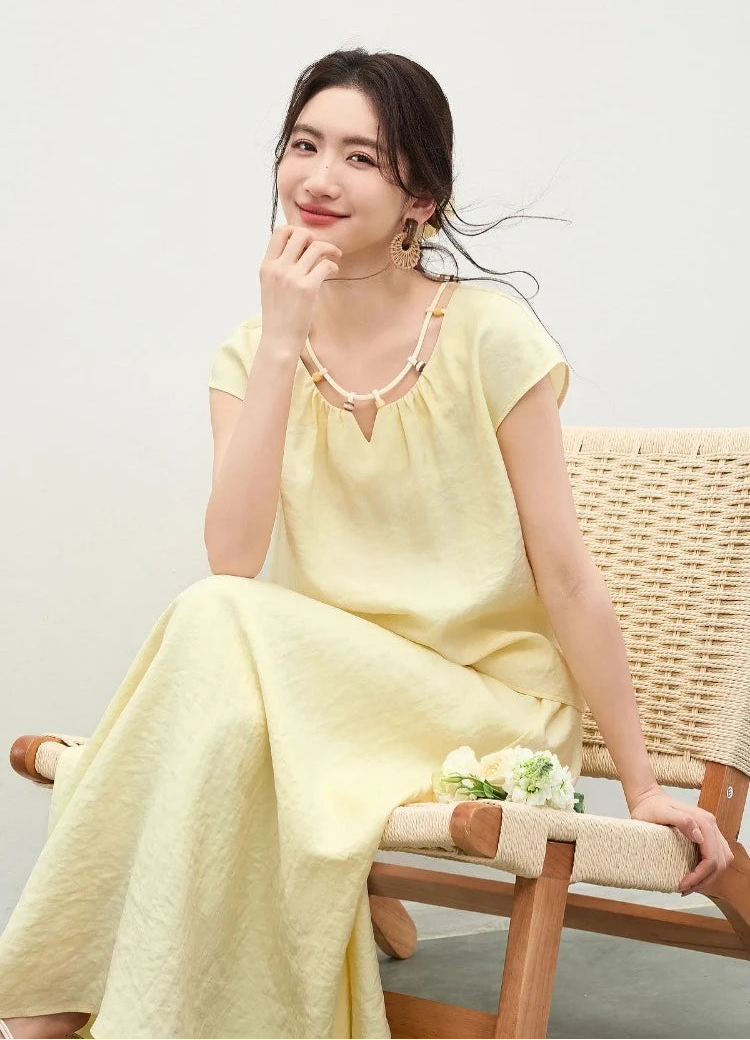 A seated woman wearing the sky blue "Her Miracle" set, pensively touching her chin, highlighting the elegant beaded neckline — From Borcelleclothes.
